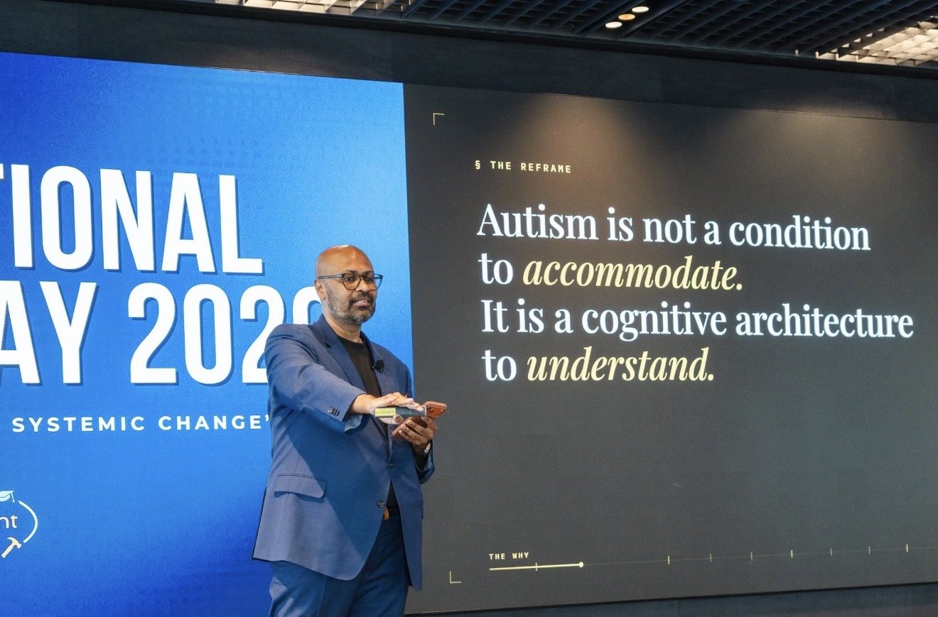 Uday Kiran Bolusani delivering The Undesigned Mind keynote at International Allyship Day 2026. The slide beside him reads 'Autism is not a condition to accommodate. It is a cognitive architecture to understand.'